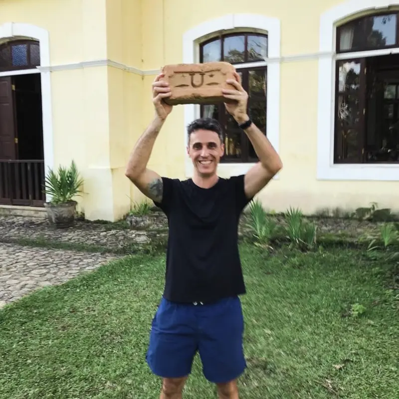 Visitante segura tijolo histórico com marca da olaria original da Fazenda Neuchatel