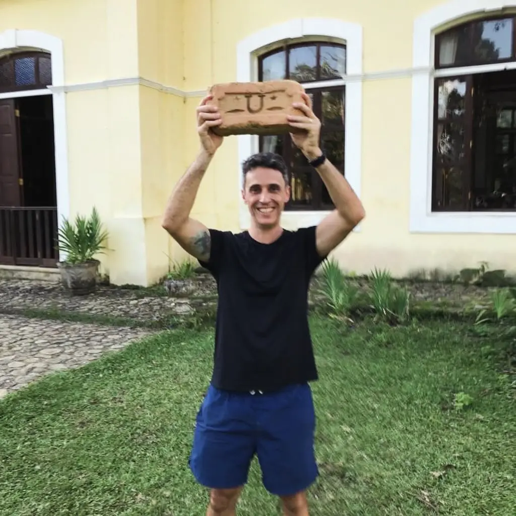 Visitante segura tijolo histórico com marca da olaria original da Fazenda Neuchatel